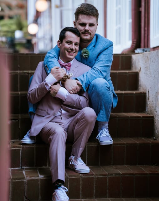 Two grooms sitting on the stairs on their wedding day